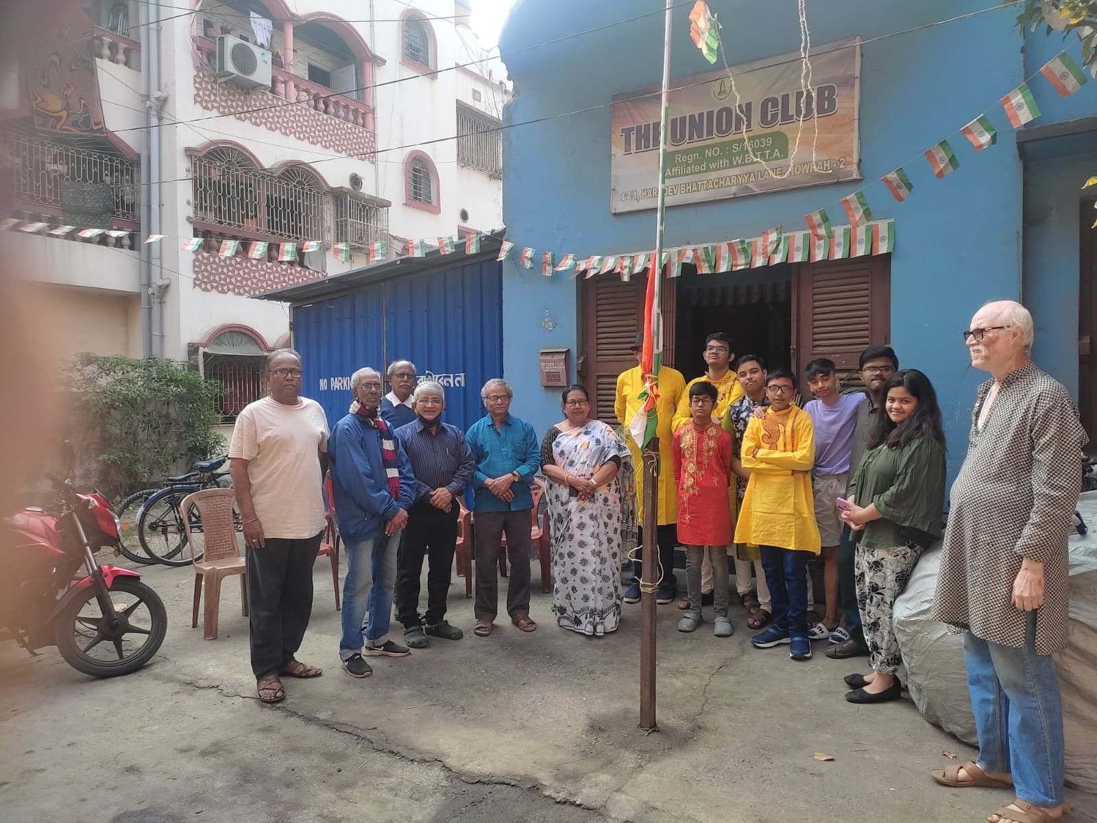 Club members, elders and young people standing together outside The Union Club building on a flag-hoisting day
