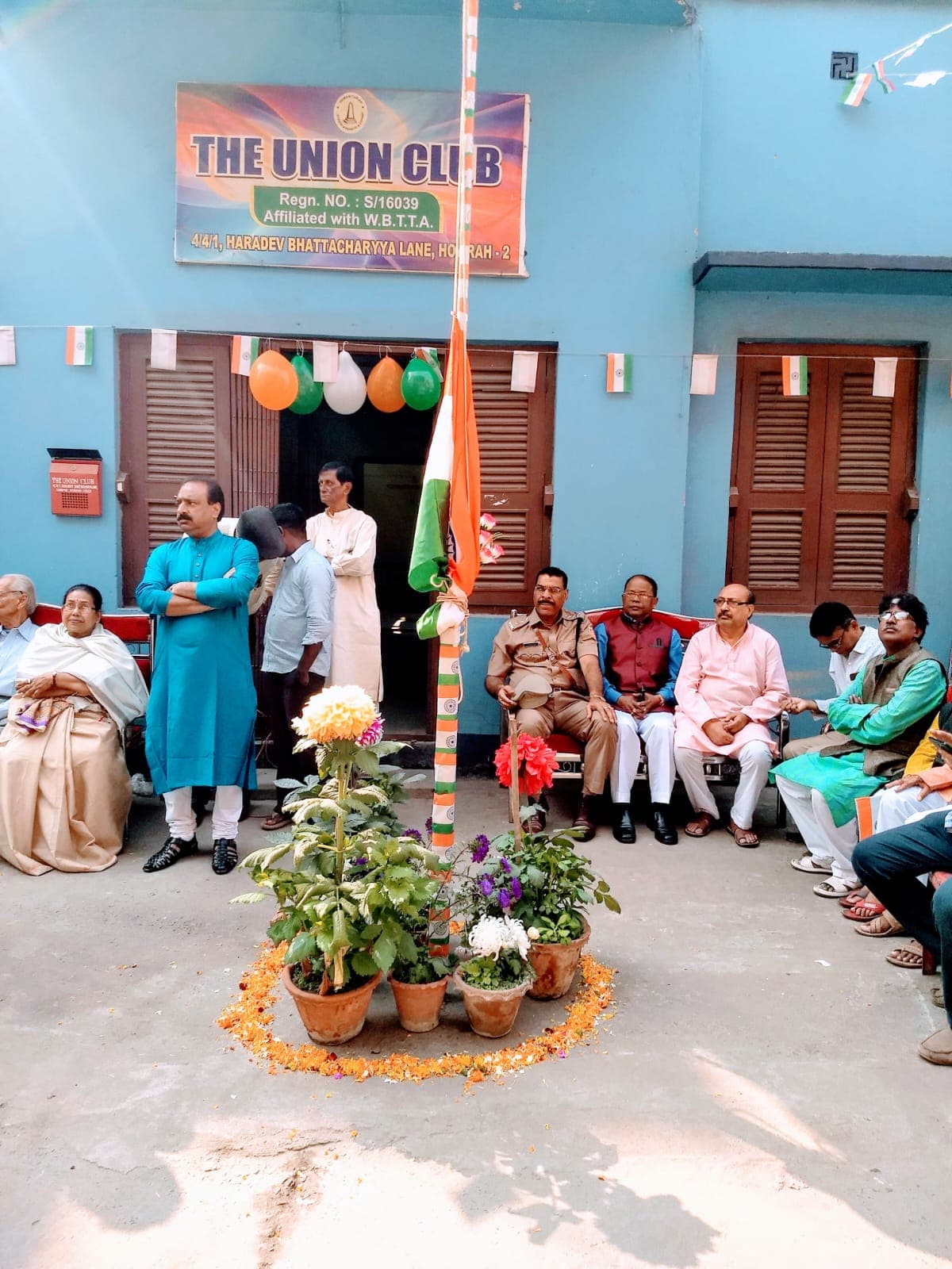 Members seated outside The Union Club building, decorated with flags and balloons for a club programme